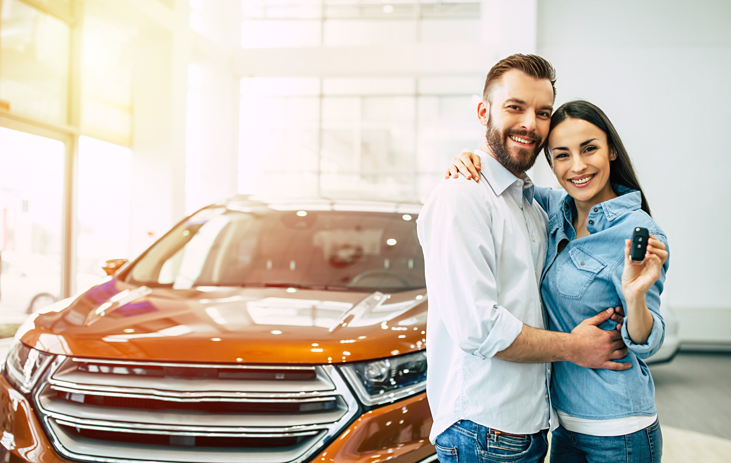 Couple holding keys and with new car